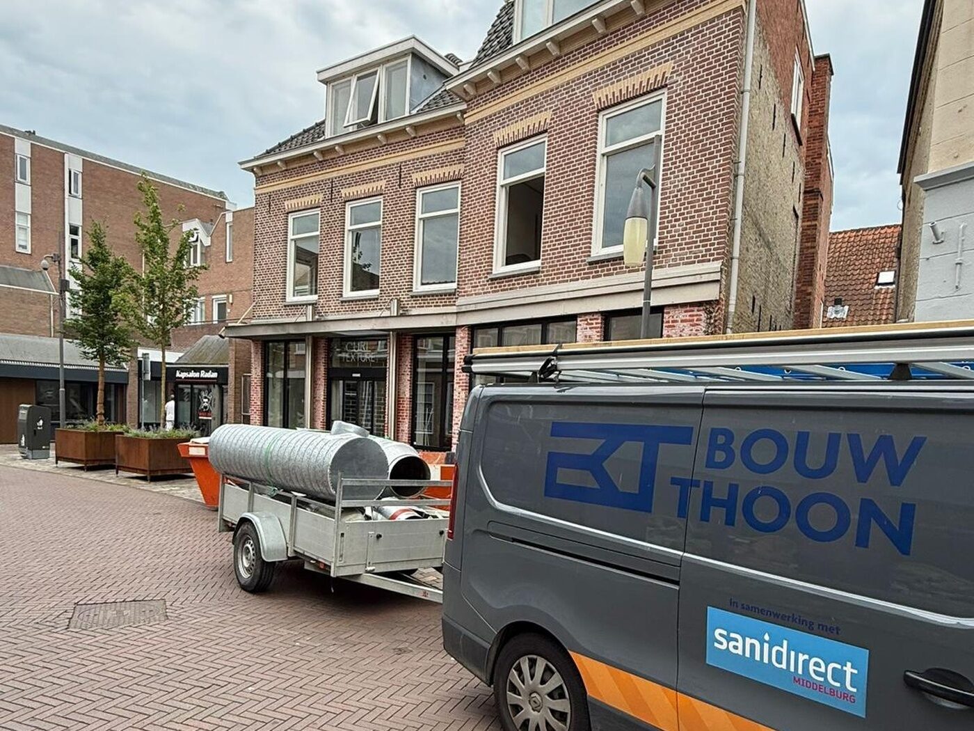 Bedrijfsbus van BouwThoon in een winkelstraat