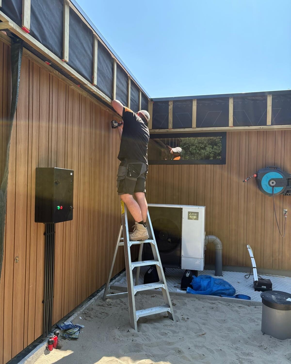 Vakman plaatst houten gevelbekleding op een aanbouw